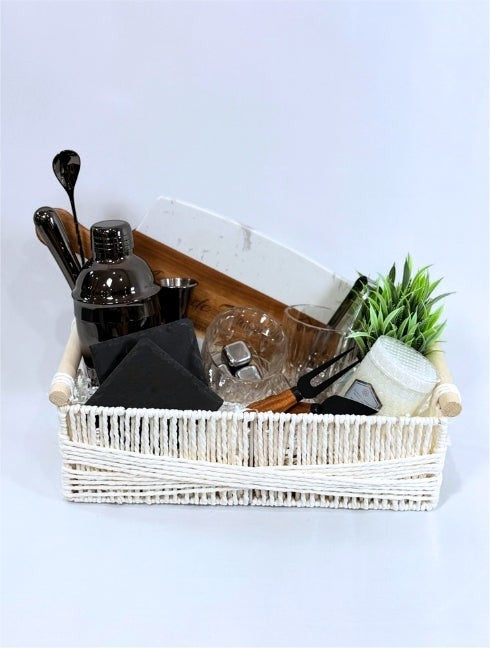Kintoir luxury cocktail gift basket featuring a shaker, glasses, coasters, and cutting board in a white woven basket.
