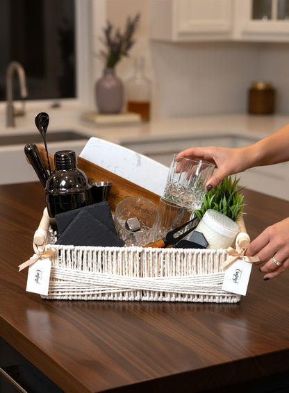 Kintoir luxury cocktail gift basket in a white woven container featuring bar tools, glassware, and a cutting board.