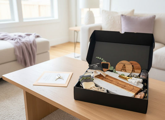 Kintoir personalized client gift box featuring an engraved cutting board, marble coasters, and accessories in a black box
