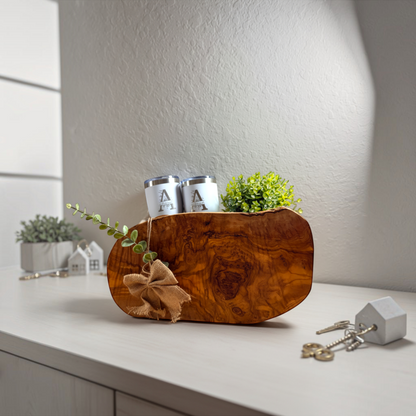 Olive wood serving board styled with greenery and white tumblers from the Grand Welcome closing gift basket