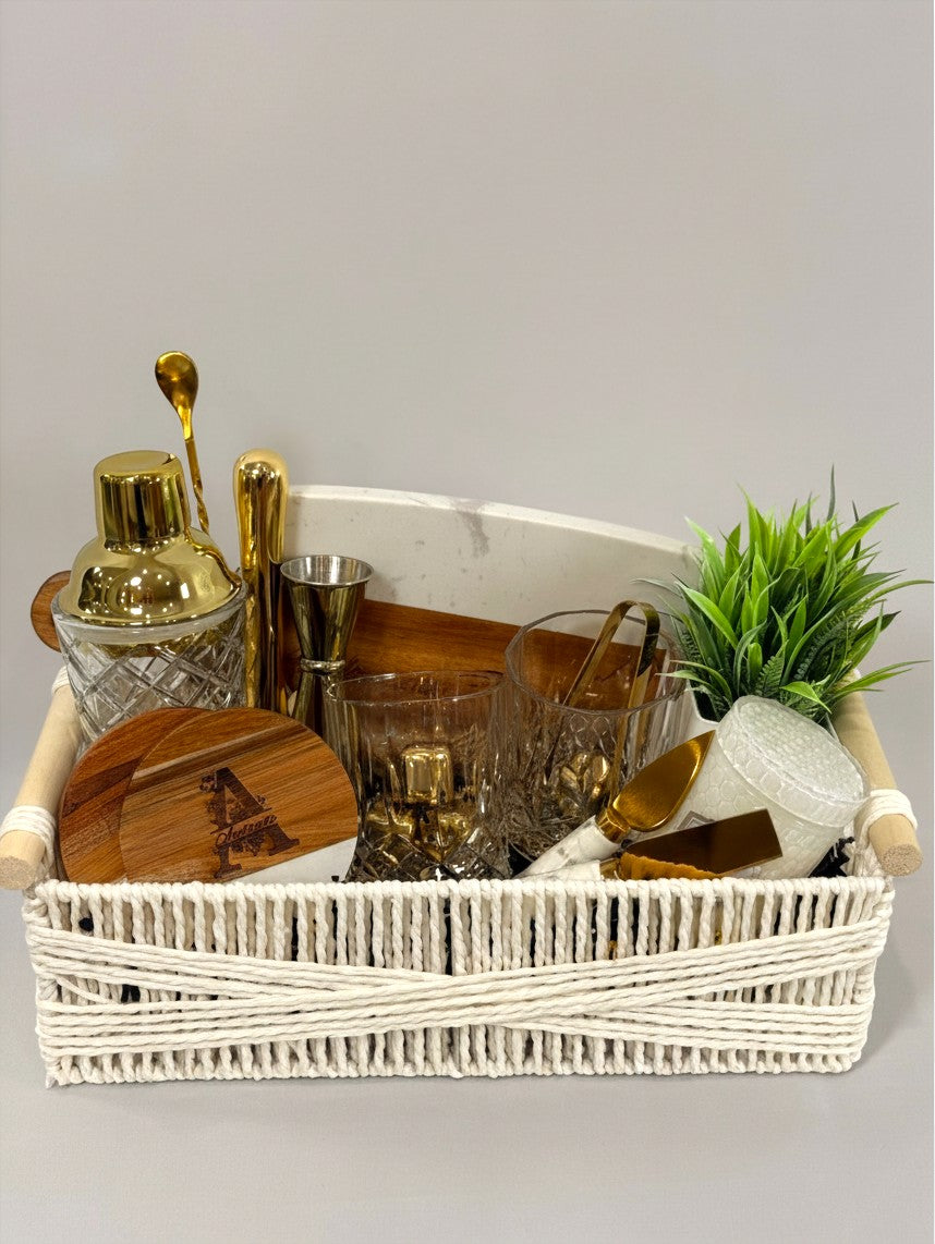 Personalized gold cocktail gift basket with engraved cutting board, cocktail tools, glasses, candle, and greenery | Kintoir