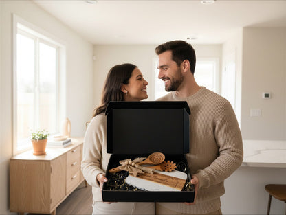 A happy couple holding a Kintoir personalized acacia wood and marble cutting board gift set in a bright home interior.