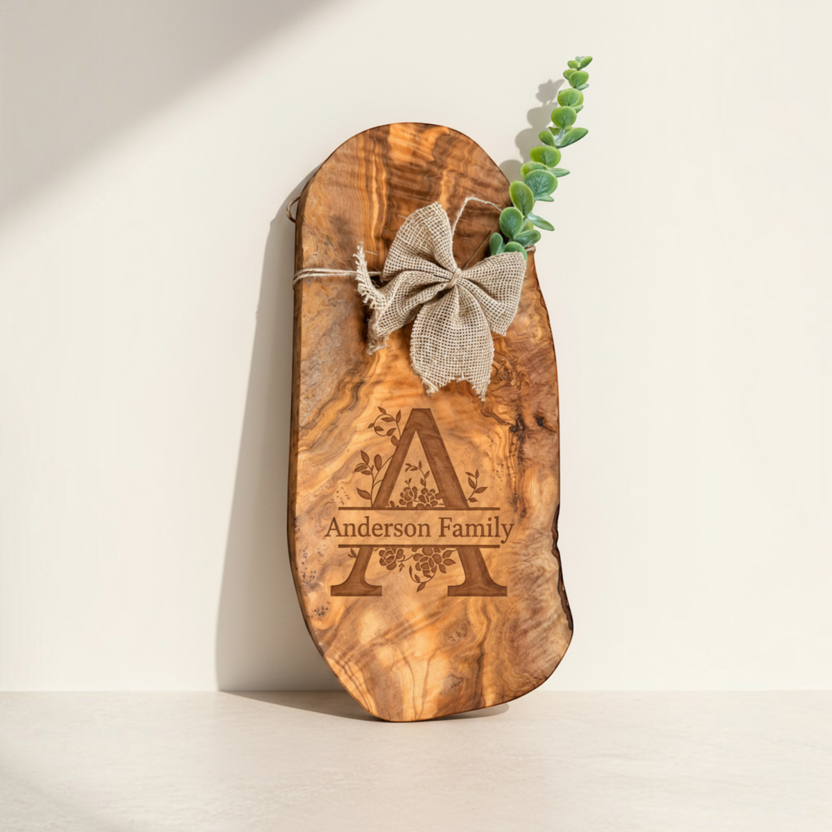 Personalized olive wood serving board with large family initial engraving, burlap bow and greenery