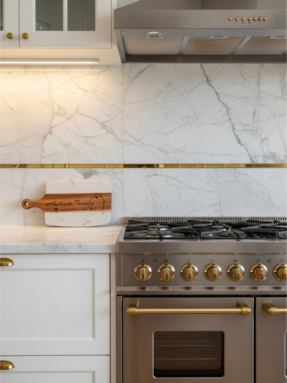 Kintoir personalized wooden cutting board with laser engraving displayed on a marble kitchen counter near a stove.
